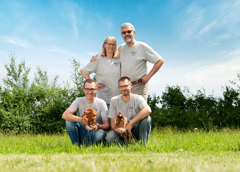 Auf dem Bild ist das Team der Firma Birkhof-Ei GmbH & Co. KG zu sehen. Die Söhne haben zwei Ihrer Hühner in den Händen. Im Hintergrund ist eine Wiese, Büsche und Himmel zu sehen.