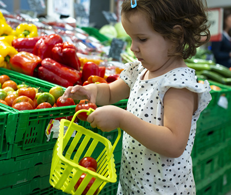 Regional Produkte einkaufen - Günstig einkaufen vor Ort - Bildinhalt: Kleines Mädchen kauft regionales Obst und Gemüse im Einkaufsmarkt mit seinem Körbchen ein.